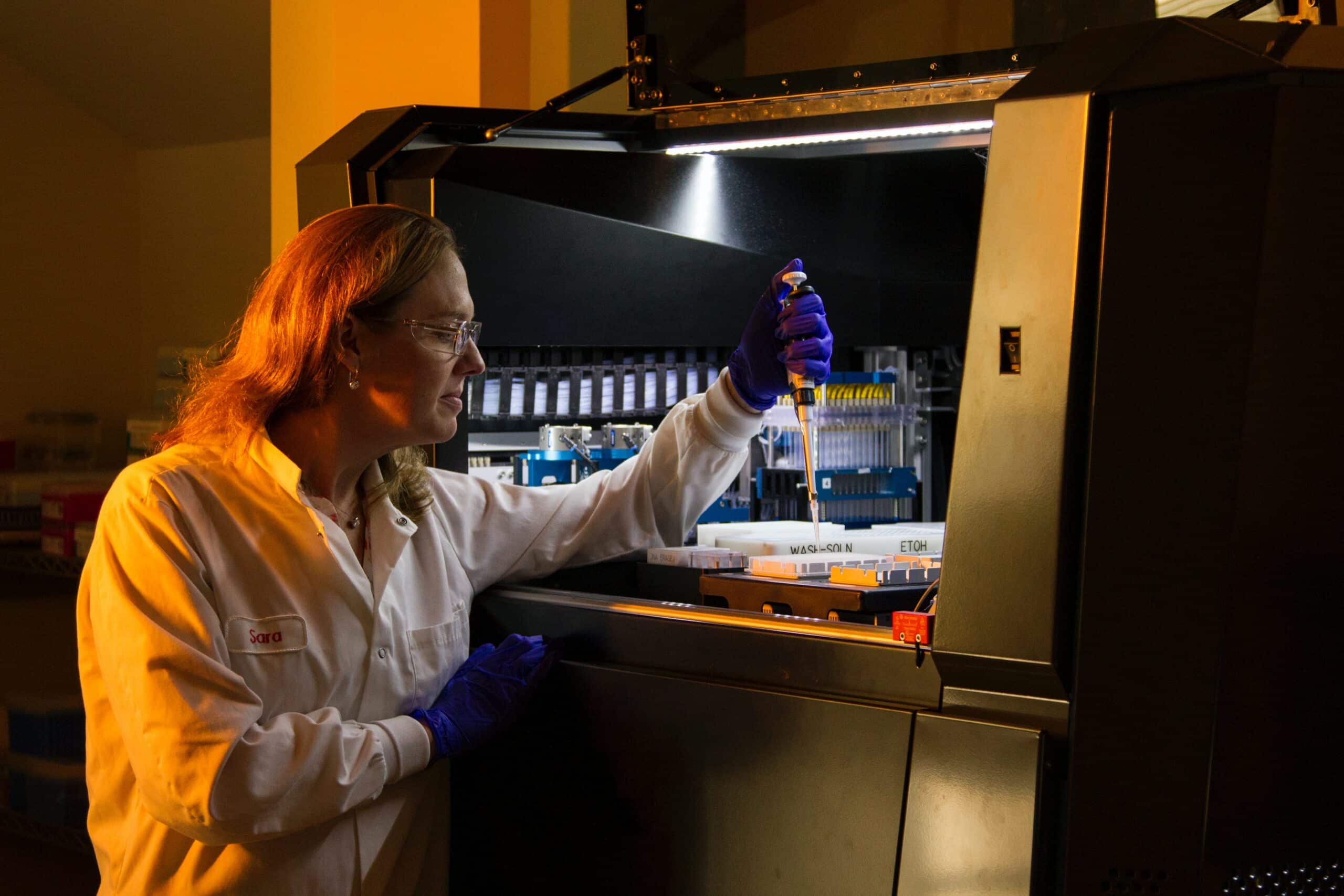 A female scientist in a dark lab room carrying out DNA sequencing.
